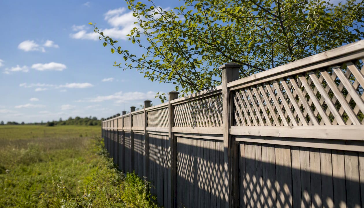 Lattice fence moving in wind on exposed lot